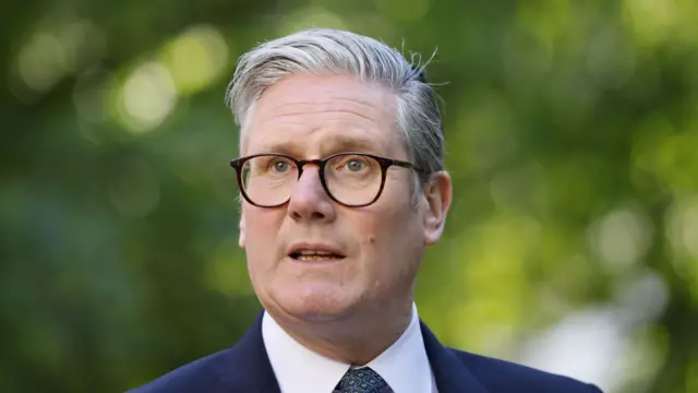 Starmer stands in front of a green background