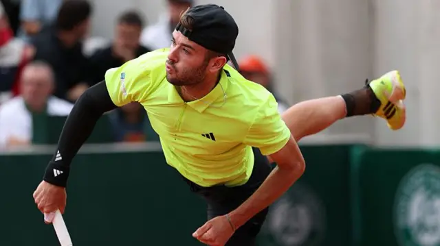 Jacob Fearnley serves against Stan Wawrinka