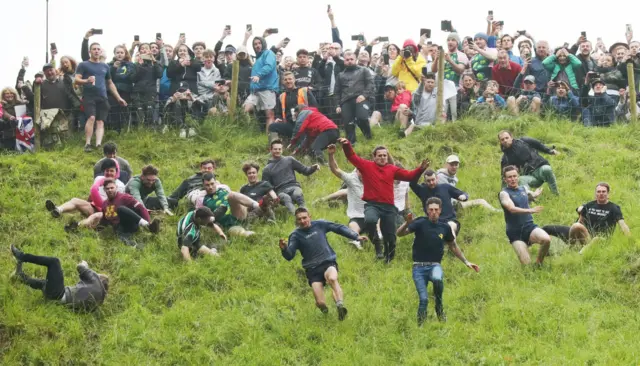 Competitors run and fall downhill during the annual Gloucester cheese rolling event