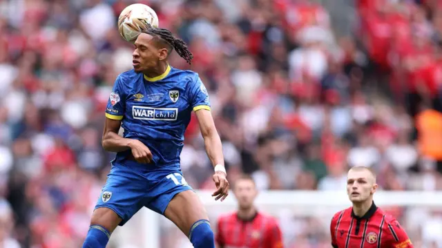 Alistair Smith heads the ball away for AFC Wimbledon against Walsall