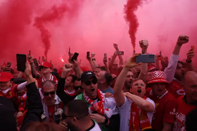 Fans celebrate amid the red mist of flares