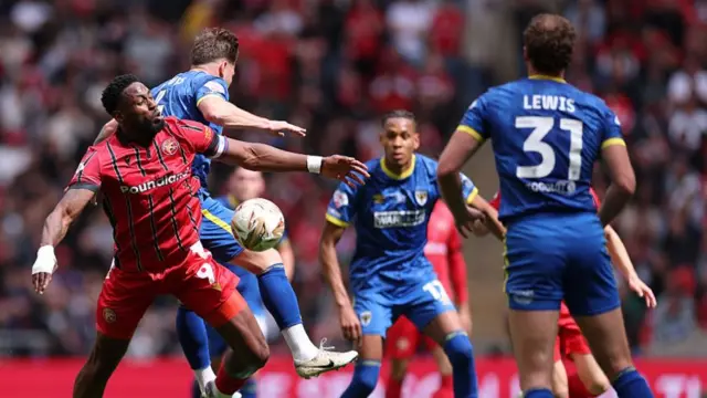 AFC Wimbledon and Walsall battle for the ball