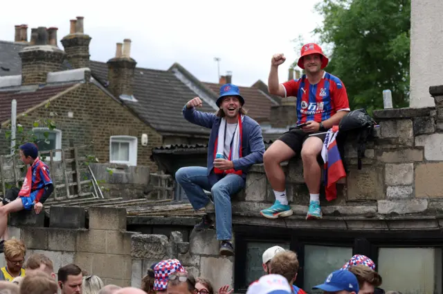 Two fans sit on a wall and cheer