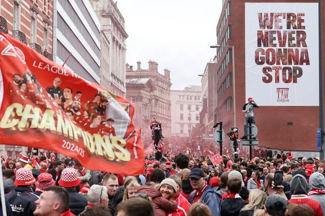 Liverpool supporters celebrate as they wait for the open-top bus victory parade for Liverpool's Premier League title win