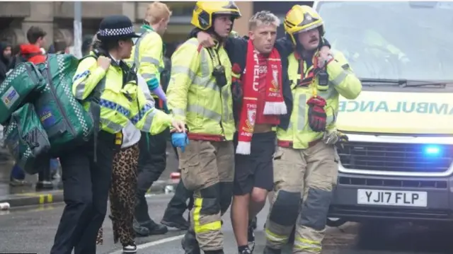 Jack Trotter is helped by two paramedics after being injured on Water Street in Liverpool