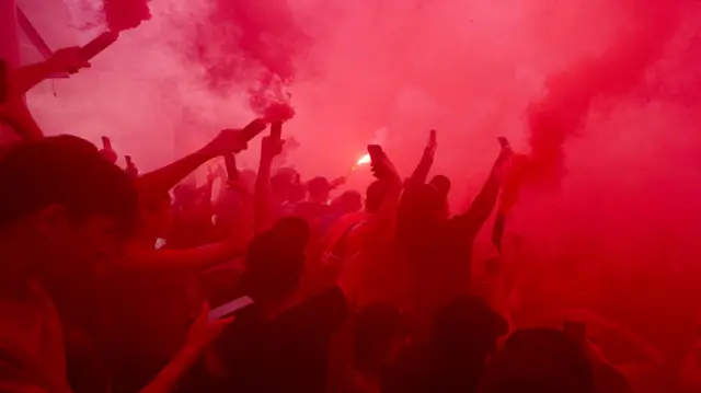 Liverpool fans set off red coloured flares outside Anfield