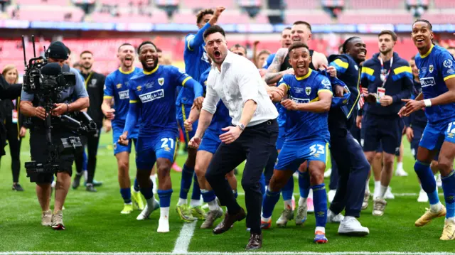 Wimbledon players and manager Johnnie Jackson celebrate on the pitch at Wembley