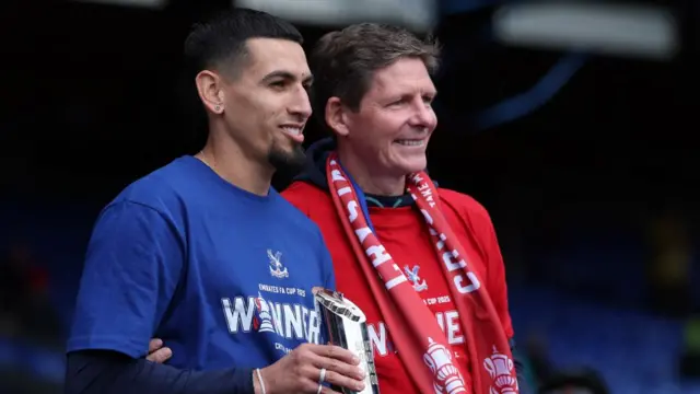 Munoz and Glasner smiling as Munoz holds a trophy