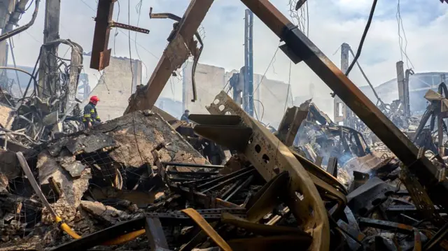 Debris of buildings with firefighters climbing up.
