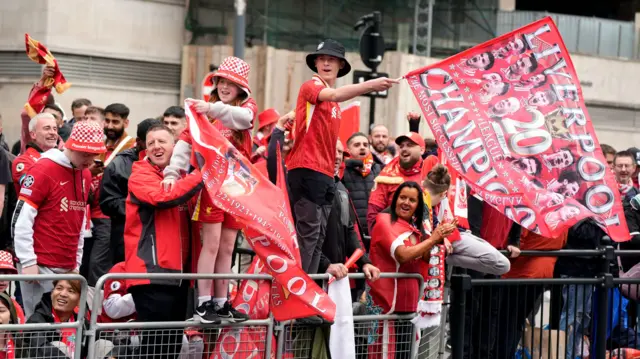Liverpool fans wave flags and wear club shirts at the parade