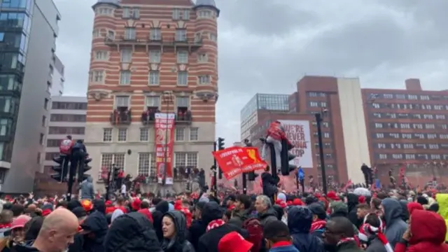 It is a sea of Liverpool fans on the strands with people climbing on traffic lights and balconies to get a good view of the parade