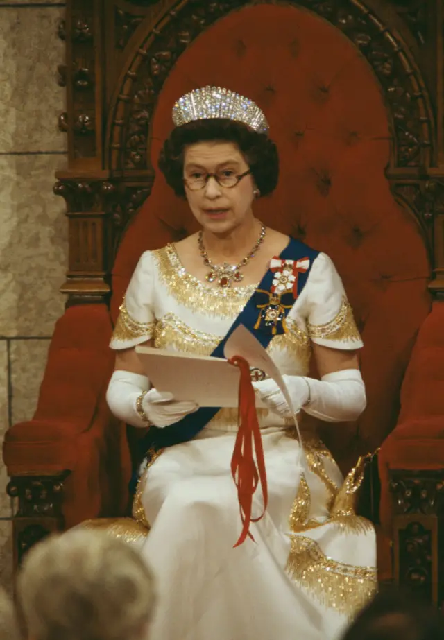 Queen Elizabeth sat on a large red throne reading the Throne speech