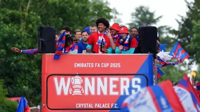 A bus with smiling players on the top deck and the word "winners" at the front