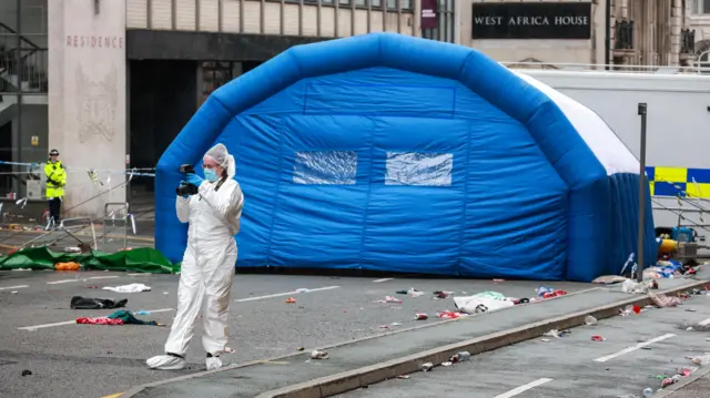 A forensic officer works near the site of an incident where a car plowed into a crowd of Liverpool fans during a parade celebrating their side's Premier League soccer title, in central Liverpool, Britain