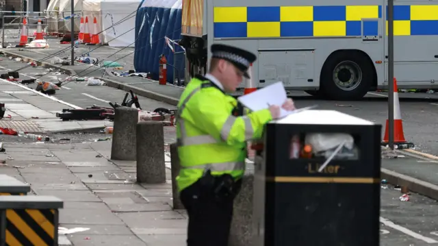 A police officer works at a crime scene after an incident where a car plowed into a crowd of Liverpool fans during a parade celebrating their side's Premier League soccer title, in central Liverpool, Britai