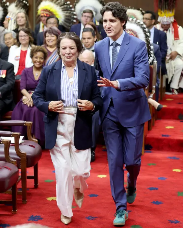 Trudeau walks through the parliament building wearing green Samba sneakers