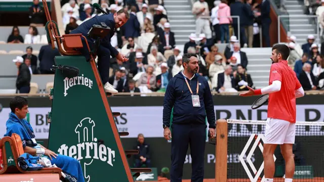 Novak Djokovic speaks with tournament official Ali Nili