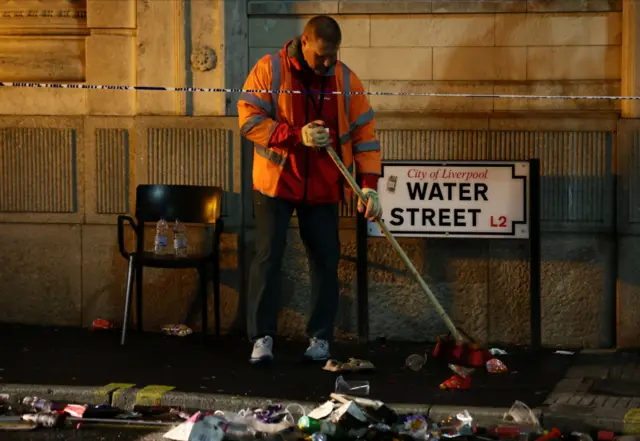 A man sweeps next to a street sign that says Water Street
