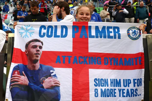 A young Chelsea fan looks on with a flag showing Cole Palmer