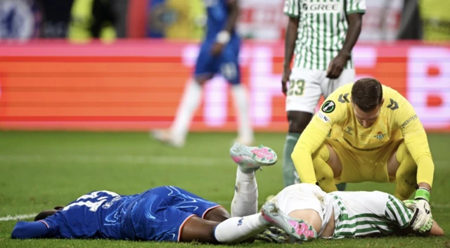 Chelsea's Nicolas Jackson (left) and Real Betis' Marc Bartra (centre right) lie on the pitch injured after colliding with Real Betis goalkeeper Adrian