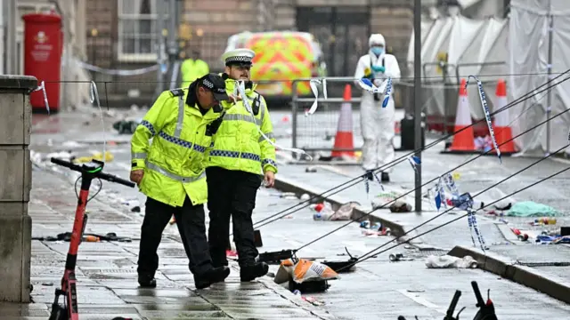 Two police officers in yellow hi-vi jackets inspect the crash scene