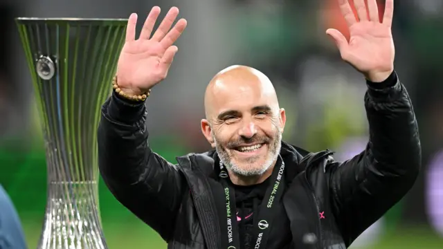 Manager Enzo Maresca smiles next to the Conference League final after Chelsea win the 2025 final