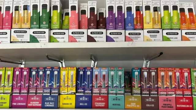 A row of vapes in boxes on a shop shelf