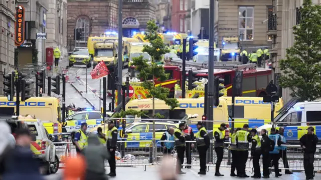 A photo of the scene in Water Street shortly after the crash. The street is cordoned off and there is a large police presence, with several emergency vehicles in the street