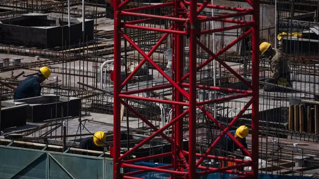 Chinese builders lay down steel pipe at a construction site
