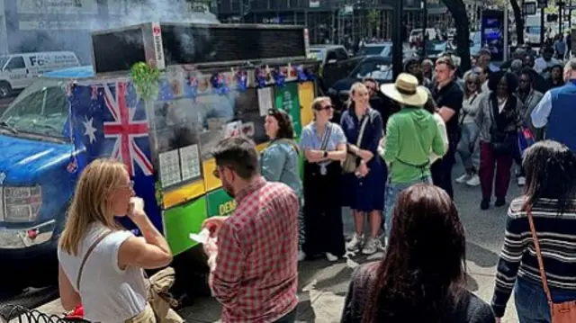 People queue at a sausage sizzle hosted by the New York Consulate.