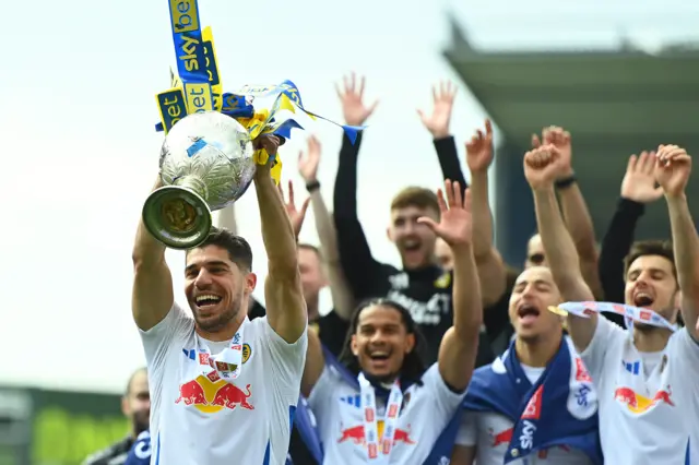 Leeds United players celebrate winning the title with the Championship trophy