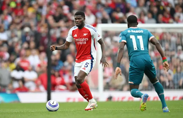Thomas Partey of Arsenal runs with the ball under pressure from Dango Ouattara