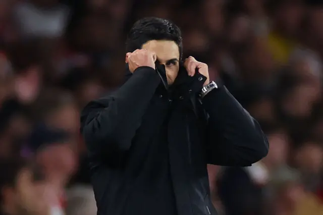 Mikel Arteta pulling his coat over his face