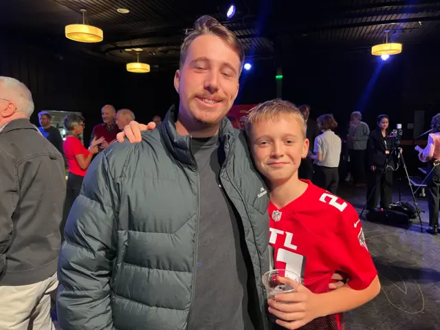 Thomas Brown in a puffer jacket with his younger brother Arlo, wearing a red football shirt