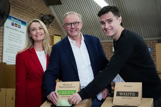 Australian Prime Minister Anthony Albanese smiles at the camera as he votes alongside his fiancée, Jodie Haydon, and his son, Nathan