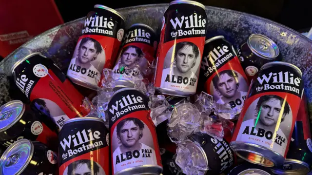 Cans of beers printed with a young Albanese, with the words Albo Pale Ale printed on them