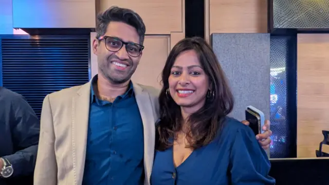 Taher and Munira Ali in navy clothes smiling at the camera