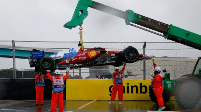 Charles Leclrec's Ferrari is lifted away by a crane