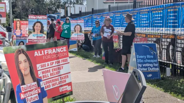 Volunteers stand near campaign posters in Peter Dutton's seat of Dickson in Queensland