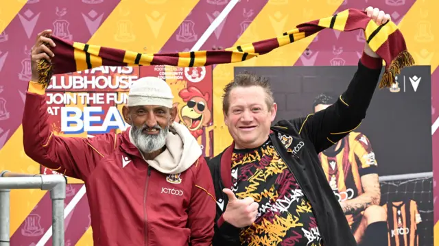 Two Bradford fans hold a scarf above their heads