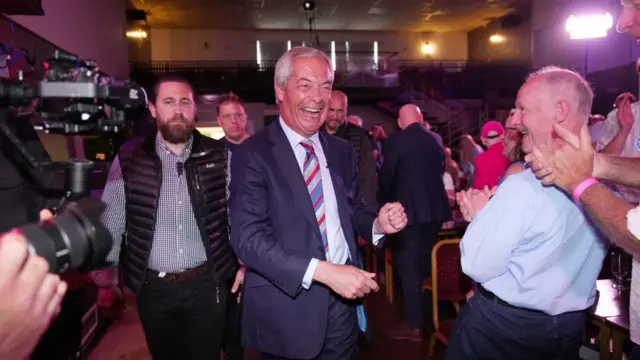 Nigel Farage walking with a smile on his face.