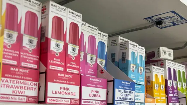 A row of refillable small colourful vapes in their packaging on a shop shelf