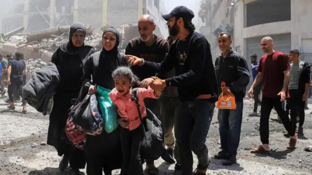 Palestinians evacuate in the aftermath of an Israeli strike on a house, in Gaza City