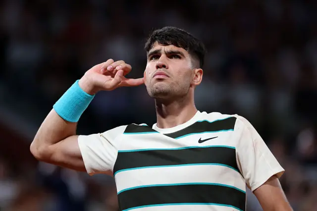 Carlos Alcaraz points to his right ear