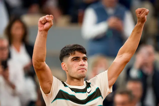 Carlos Alcaraz holds his arms in the air