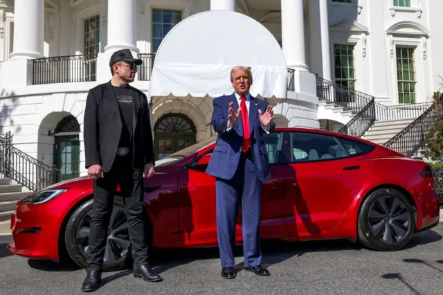 Musk and Trump stood in front of a red Tesla in front of the White House