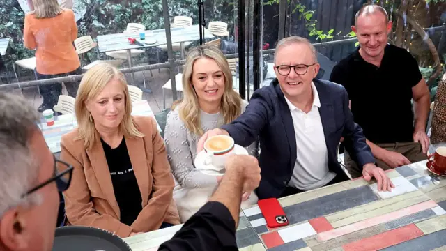 Prime minister Anthony Albanese and his partner Jodie Haydon pick up their coffee while visiting his Sydney electorate on 4 May 2025