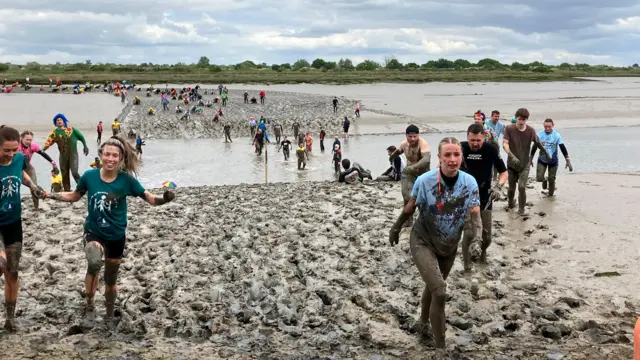 A wide shot showing several people covered in mud.