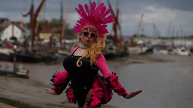 Person dressed up in a pink and black feathery outfit, posing with a "kissy face"