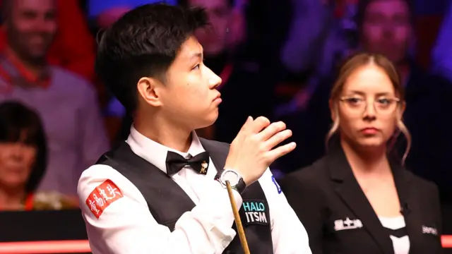 Zhao Xintong swats away a fly